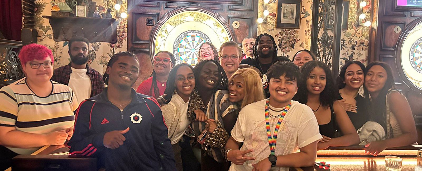a group of male and female students smiling and laughing in a bar venue
